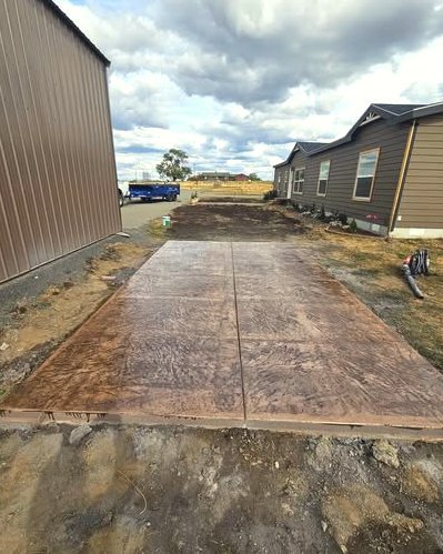 Brown stamped concrete pad beside a metal building and manufactured homes in Huntersville, NC