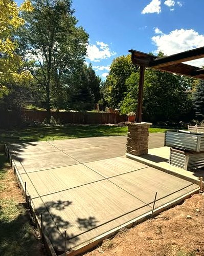 Concrete patio with forms beside a pergola and a stone column in Huntersville, NC
