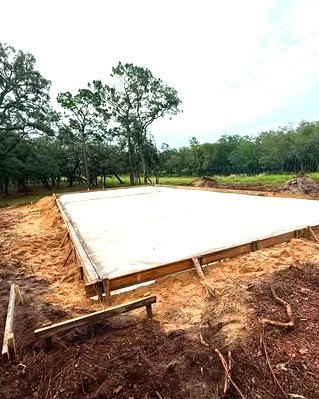 Large concrete slab poured in wood forms among tall oak trees in Huntersville, NC