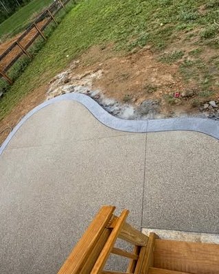 Exposed aggregate concrete patio with a curved border beside wood stairs in Huntersville, NC