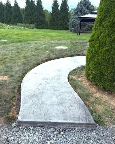 Curved gray stamped concrete walk through a lawn beside a gazebo in Huntersville, NC
