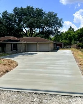 Wide gray concrete driveway leading to a brick ranch home under a big oak in Huntersville, NC