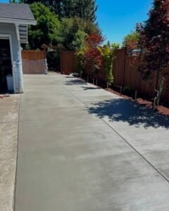 Long gray concrete driveway beside a house and a wood fence in Huntersville, NC