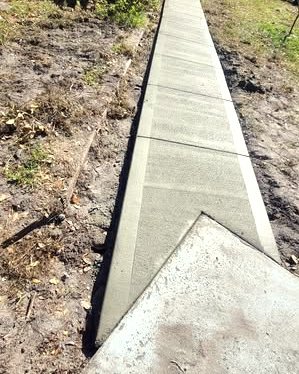 Gray concrete sidewalk with a curb cut along a grassy lot in Huntersville, NC
