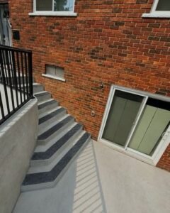 Gray concrete steps with black nosing and a railing beside a brick home in Huntersville, NC