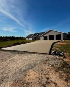 New gray concrete driveway sweeping toward a ranch home with a three car garage in Huntersville, NC